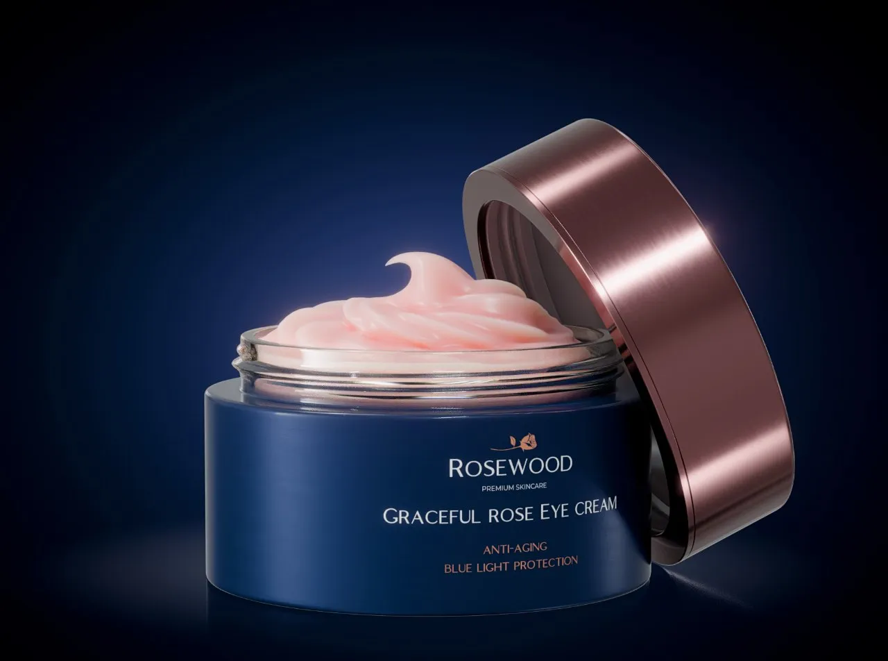Open navy Rosewood Graceful Rose Eye Cream jar with pink cream and a tilted rose-gold lid against a dark blue background