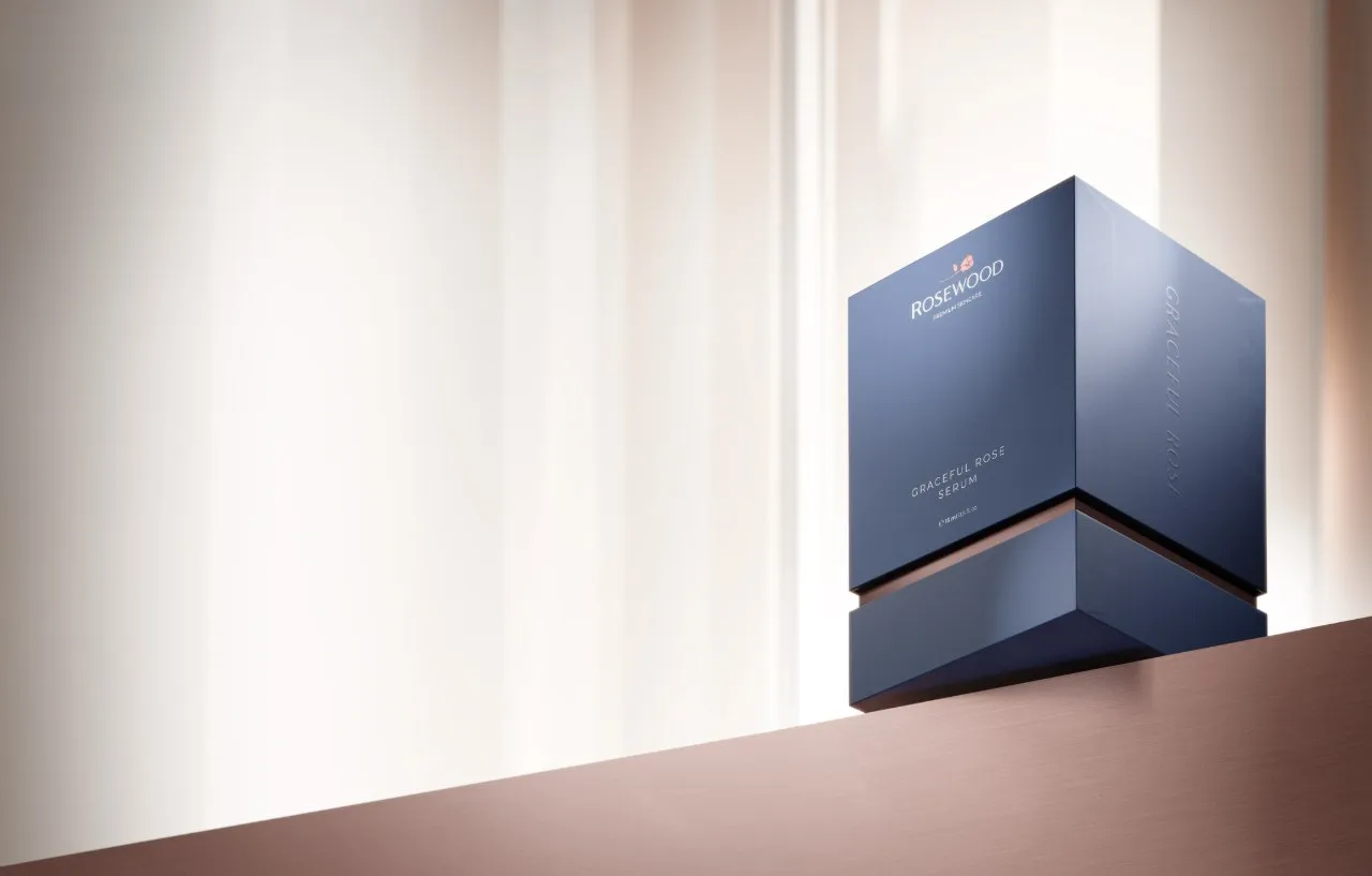 Navy Rosewood Graceful Rose Serum presentation box raised above its base on a warm ledge in soft window light