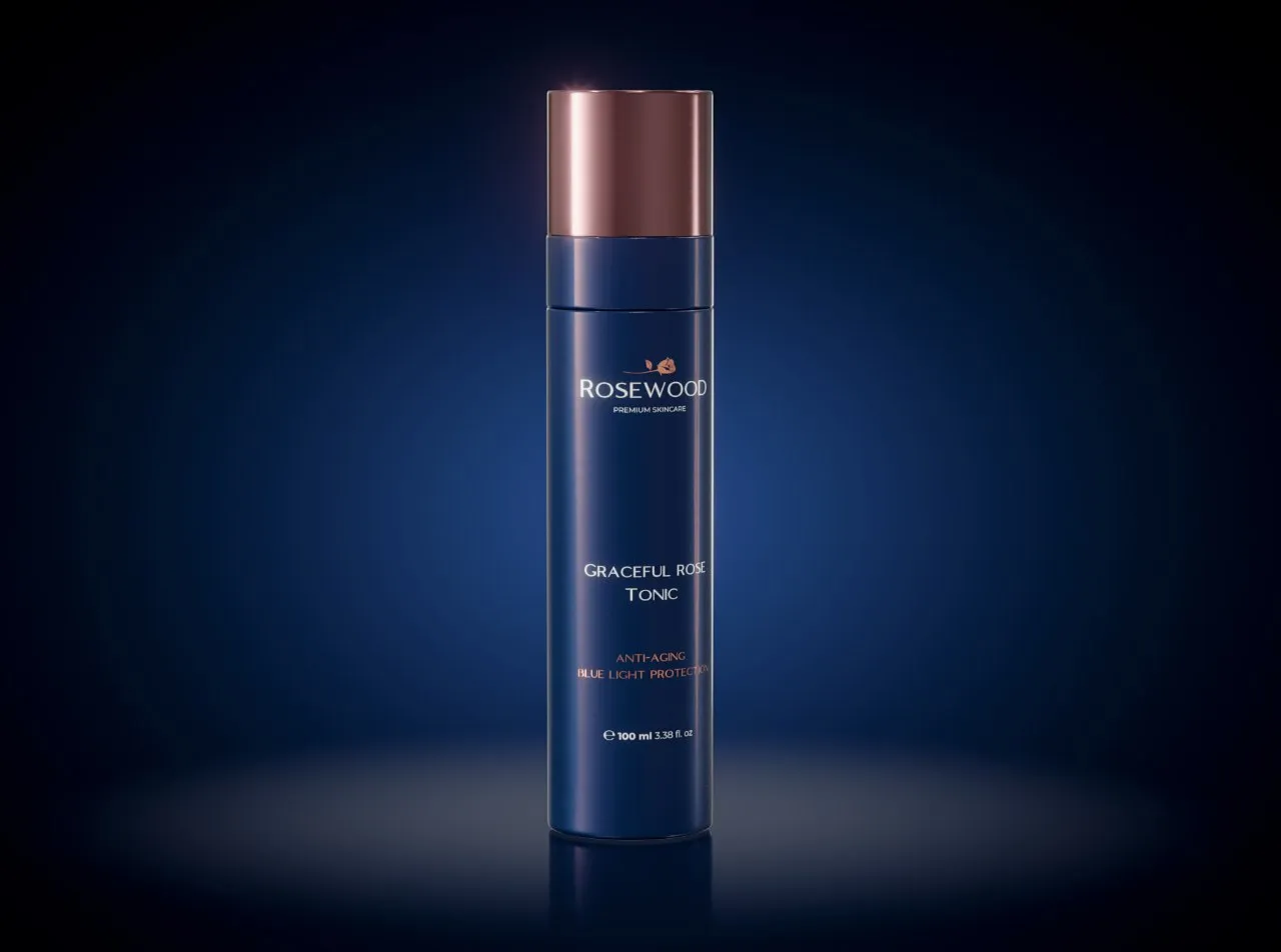 Rosewood Graceful Rose Tonic bottle with a rose-gold cap, standing on a dark reflective surface against a blue glow